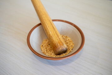 Japanese sesame grinding bowl and wooden stick. Wooden bowl with white sesame for grinding on wooden table.