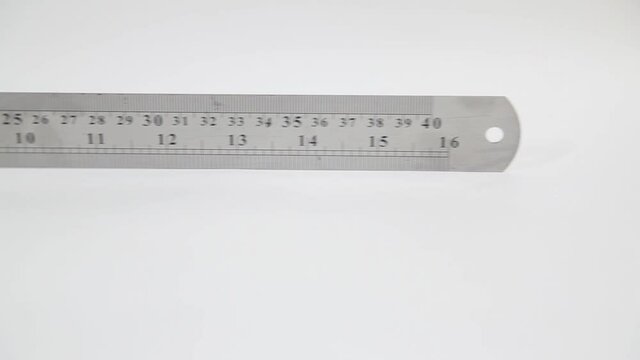 Slow panning of stainless steel ruler with inches and centimeters on white 
