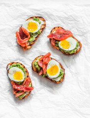 Cream cheese, avocado, red salted fish, boiled egg sandwiches on a light background, top view