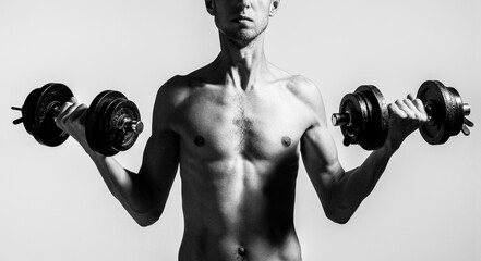 Fototapeta na wymiar Man holding dumbbell in hand. Skinny guy hold dumbbells up in hands. A thin man in sports with dumbbells.Black and white