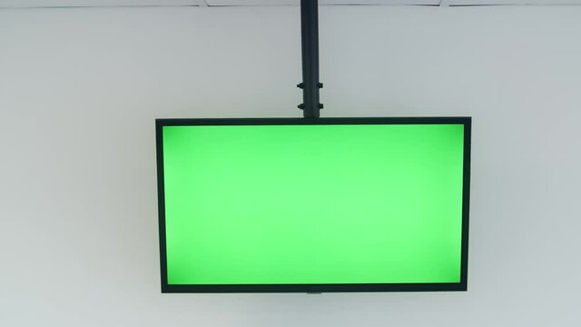 Big green screen TV in a white well lit conference room with nobody in it