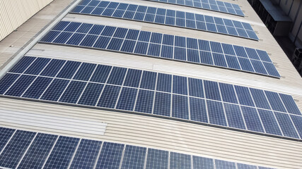 Obraz premium Solar panels installed on a roof of a large industrial building or a warehouse. Industrial buildings in the background. Horizontal photo.