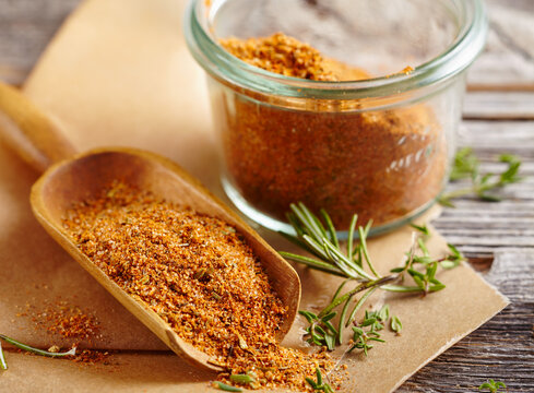 Homemade steak spice mix in a glass and on a wooden scoop