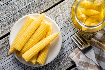 Pickled young baby corn cobs on plate.