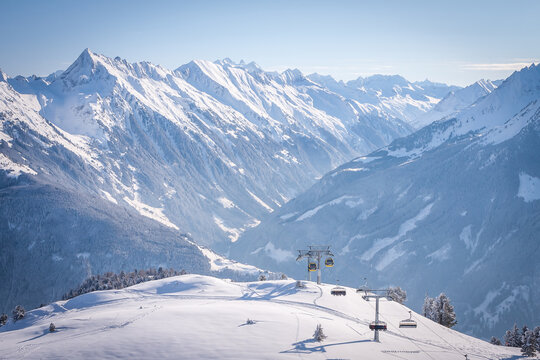 Panorama of Mayrhofen with ski lifts and cable car, Zillertal, Austria. Penken ski area. Mountains and fir trees covered with snow. Frosty morning