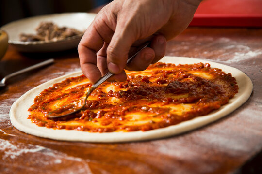 Adding tomato sauce to pizza