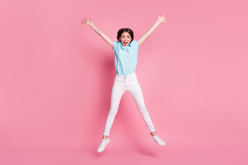 Fototapeta na wymiar Full length photo of crazy carefree girl jump raise hands isolated over pink color background