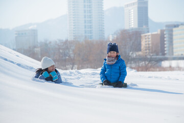 Happy Asian children lying on snow together in the park
