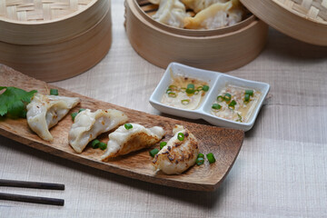 Fried gyoza and dumplings snack with plum sauce on wooden table.