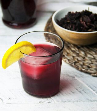 A Glass Of Cold Sorrel Drink With Lemon Wedge Garnish With Sorrel Leaves In Bowl