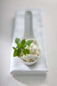 Crumbled feta with fresh oregano on a porcelain spoon