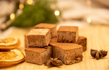 Fragrant spices and marshmallows on a wooden tray, decorated with fir branches and a festive garland.