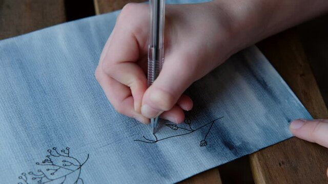 little girl draws plants and flowers on a sheet of paper with watercolors and pencils, children's creativity and drawing, concept