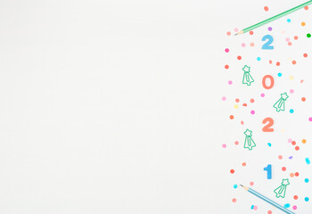 Multi-colored soft English numbers 2021 with school and office supplies: clips, pencils on white background with paper confetti. Back to school, Christmas in office concept. Flat lay, copy space.