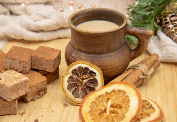 A brown ceramic mug, sweets and aromatic spices stand on a wooden tray .
