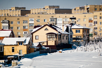 Obraz premium Multi-storey residential buildings made of white and red brick with plastic Windows, stand in winter under a layer of white lush snow in frosty Sunny weather.