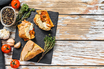 Baguette stuffed with eggplants, tomatoes and cheese. A delicious vegetarian lunch, tasty snacks, homemade sandwich.  Gray background. Top view. Copy space