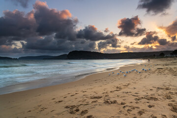 Cloudy sunset at the beach with seagulls and waves