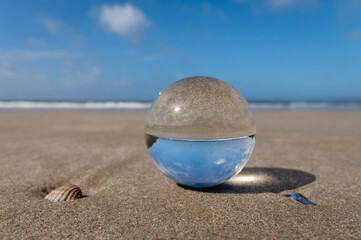 Fototapeta na wymiar Glass sphere lying on a beach on a sunny day