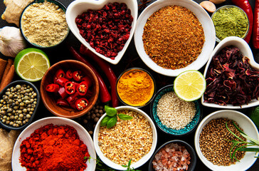 Various spices in a bowls on black concrete background. Top view copy space.