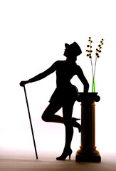 A silhouette of a young girl is seen leaning on a stone 
pillar on a stage. She holds her dance...