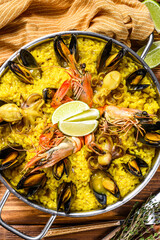 Seafood paella in the fry pan with prawns, shrimps, octopus and mussels.  Wooden background. Top view