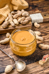 Obraz na płótnie Canvas Fresh made creamy Peanut Butter in a glass jar. Wooden background. Top view