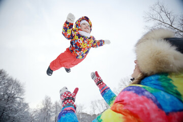 small child and young mother in the winter outside in warm clothes fun