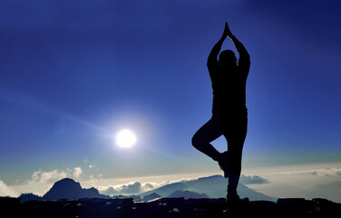 silhouette of a girl practicing yoga, woman doing yoga on the top of the mountain. prayer background.