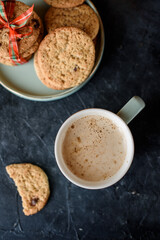 Delicious shortbread with pieces of chocolate in a small plate, aromate coffee, toys on the Christmas tree, sprigs of spruce, gifts, view from above.
