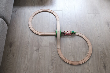 Eight shape wooden toy train circuit on an indoor wooden floor