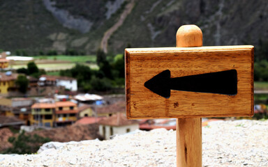 A sign with a big arrow pointing to the left. In the background it's possible to see a village....