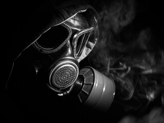 Fototapeta na wymiar Gas mask in smoke on a black background close up