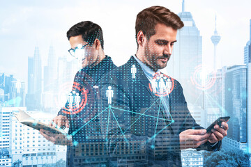 Two handsome young SMM specialists working on social media marketing strategy to achieve business goals. Hologram icons over Kuala Lumpur background.