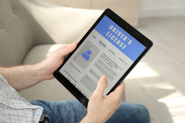Man holding tablet with driver's license application form at home, closeup