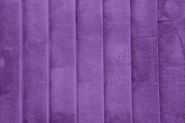 Fototapeta premium Surface of the wall with a decorative purple plaster. Textured purple concrete wall with vertical lines and stripes as a texture or background. Repair, design concept.