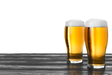 Glasses of tasty beer on black wooden table against white background