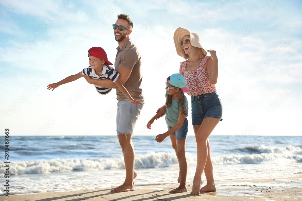 Wall mural happy family having fun on sandy beach near sea