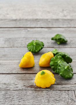 Mini yellow and green patty pan squash on a rustic wooden table