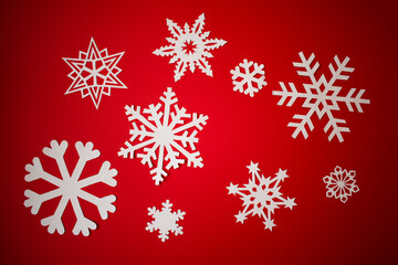 Fototapeta na wymiar Various paper cut out snowflakes on red background