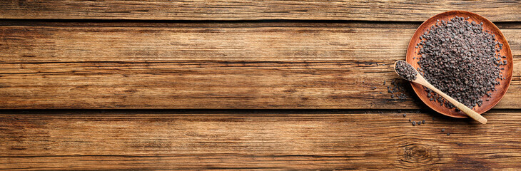 Black salt on wooden table, top view. Space for text