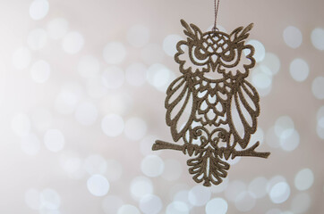 White toy owl. Bokeh. Silver Christmas lights.