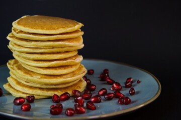 pancakes close-up on a dark background, ready for breakfast, with pomegranate berries