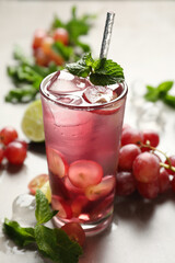 Soda water with grapes, ice and mint on table. Refreshing drink