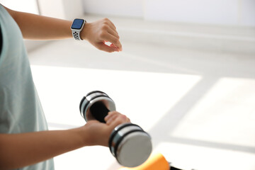 Woman checking fitness tracker in gym, closeup