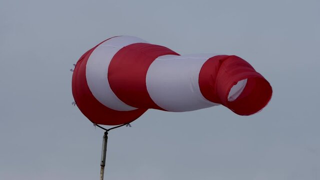 Windsock with cloudy sky in the background. conical tube in fabric reminiscent of a giant sock used as a basic guide for the direction and speed of the wind or as a decoration