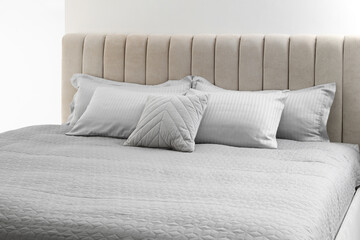 Many soft pillows on large comfortable bed indoors