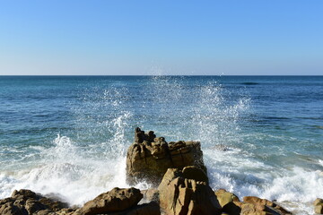 Fototapeta na wymiar Waves breaking against the rocks with blue sky. Rias Baixas, Galicia, Spain.