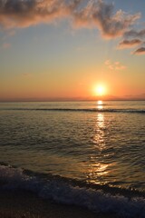 Obraz premium Golden reflection of sunset on the shore of a calm ocean