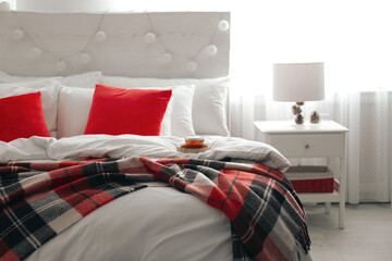 Comfortable bed with warm checkered plaid in stylish room interior